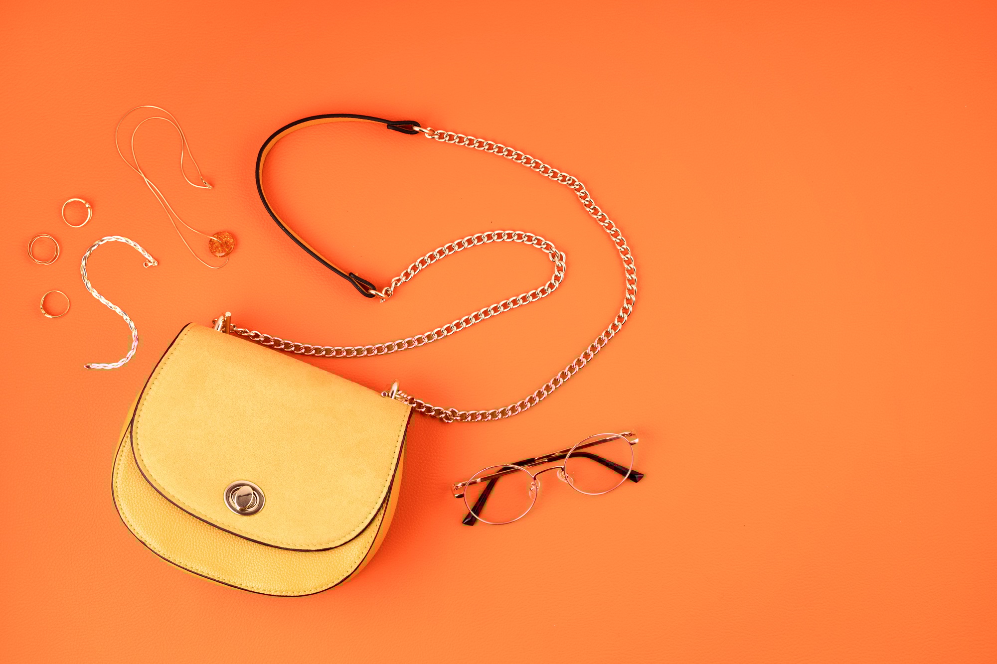 Flat lay with woman fashion accessories in yellow color over orange yellow textured background